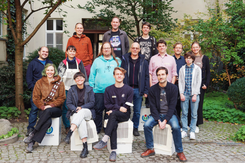 Das Foto zeigt mehrere Menschen in einem grünen Innenhof, die für ein Foto zusammenstehen. Sie sind Teil eines Netzwerks von OK Labs, kurz für Open Knowledge Labs, in ganz deutschland.