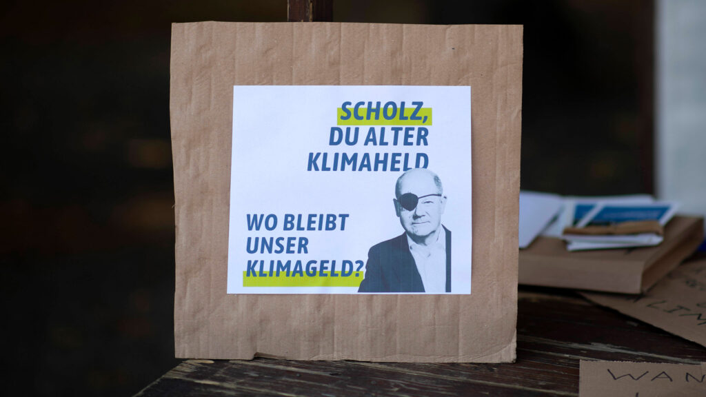 Plakat am Rande des globalen Klimastreiks in Berlin. Darauf zu sehen: Kanzler Scholz mit Augenklappe und die Frage an ihn: Scholz, Du alter Klimaheld - wo bleibt unser Klimageld?