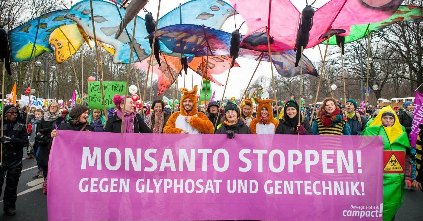 Wir haben es satt: Monsanto stoppen! Gegen Glyphosat und Gentechnik - steht auf einem Schild das Demonstranten hochhalten