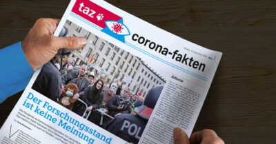 Ein Mensch hält eine Zeitung in den Händen - das Corona-Dossier der taz.