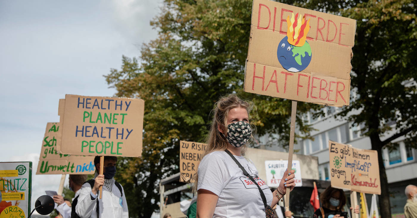 Einige Personen demonstrieren für den Klimaschutz mit Pappschildern.
