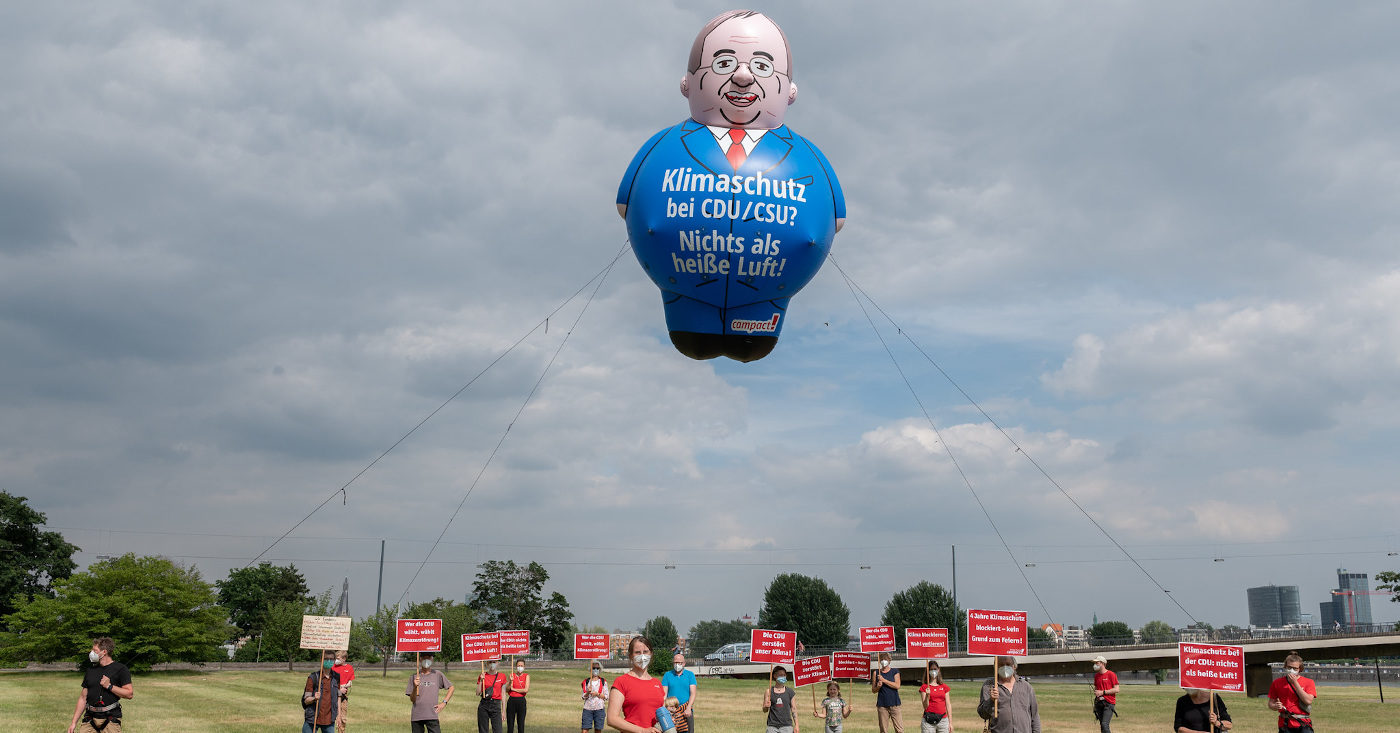 Mehrere Personen stehen mit Roten Schildern auf einem Feld und lassen einen großen Laschet-Ballon mit der Aufschrift: "Klimaschutz bei CDU/CSU? Nichts als heiße Luft" steigen. Eine Aktion zur Menschenkette am Kohletagebau Garzweiler: Klima schützen, Kohle stoppen!