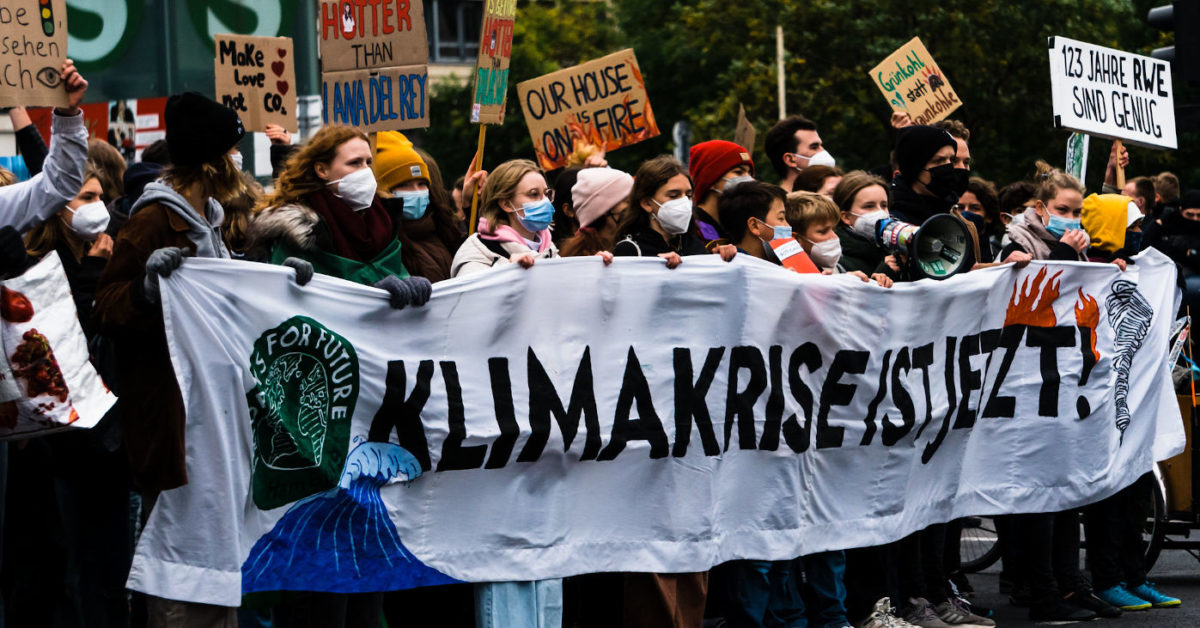 Demonstrierende Jugendliche beim Klimastreik in Berlin am 22. Oktober 2021. Sie tragen ein großes Banner mit der Aufschrift "Klimakrise ist jetzt" und viele Plakate.