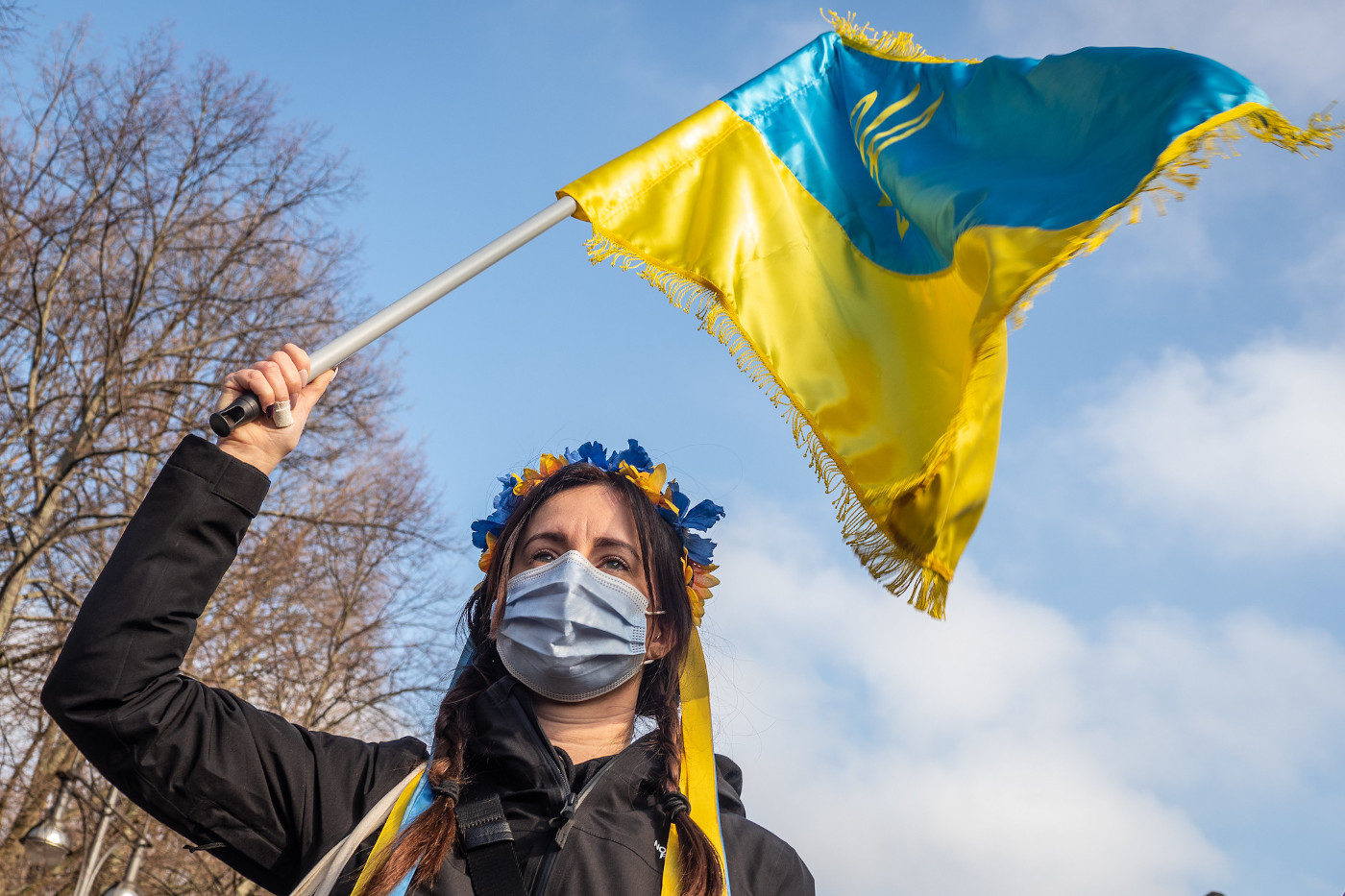 Auf einer Friedensdemo in Solidarität mit der Ukraine schwingt eine Demonstrantin eine Ukraine-Flagge.
