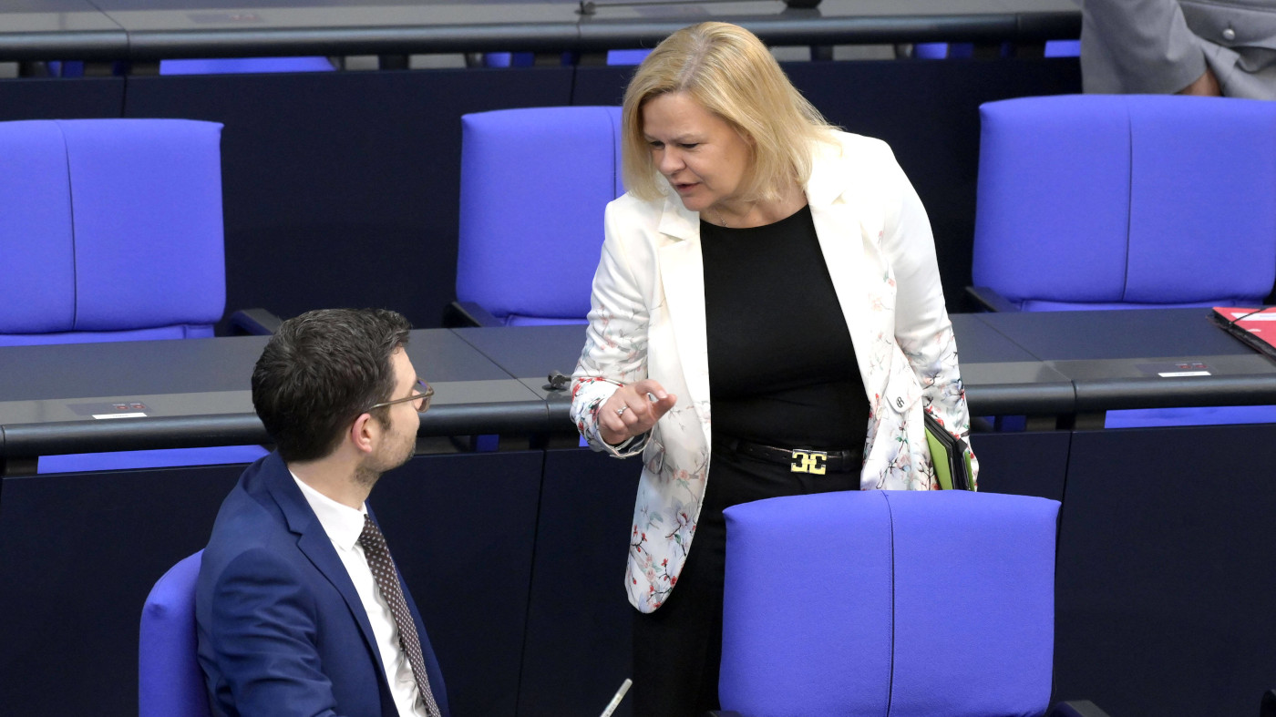 Das Foto zeigt Justizminster Marco Buschmann von der FPD und Innenministerin Nancy Faeser von der SPD gemeinsam im Bundestag. Sie unterhalten sich.