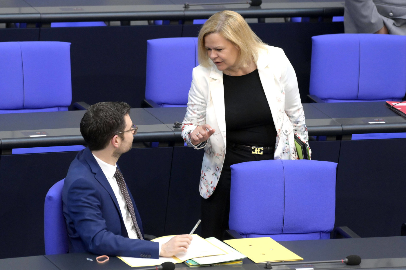 Das Foto zeigt Justizminster Marco Buschmann von der FPD und Innenministerin Nancy Faeser von der SPD gemeinsam im Bundestag. Sie unterhalten sich.