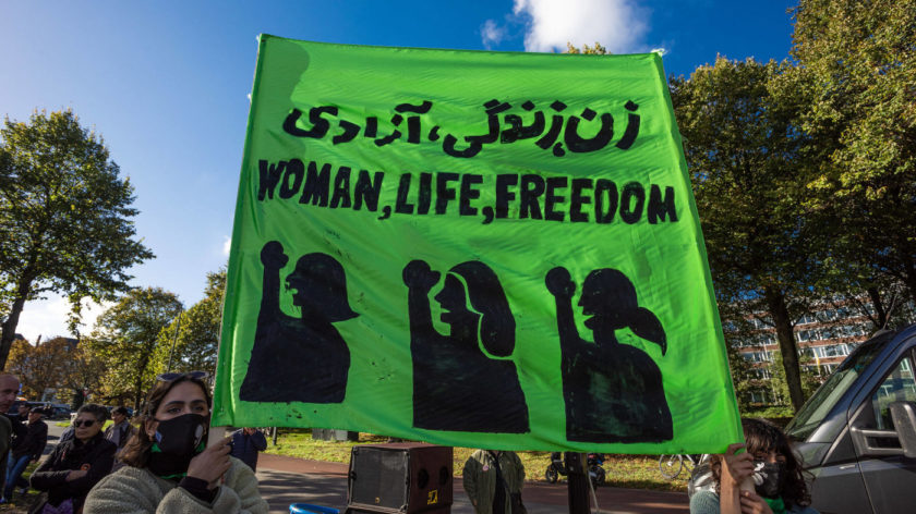 Zwei Frauen halten ein grünes Banner hoch, auf dem steht "Woman, Life, Freedom". Grund der Demo sind die Morde im Iran nach dem gewaltsamen Tod von Jina Amini, auch Mahsa Amini genannt.
