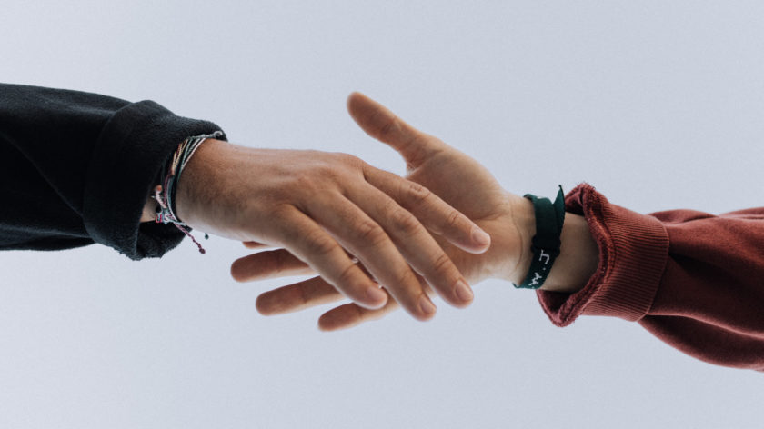 Das Foto zeigt zwei Hände, die zueinander hingestreckt sind, als würden sie sich gleich fassen. Es ist ein Symbol für Hilfe und Solidarität.