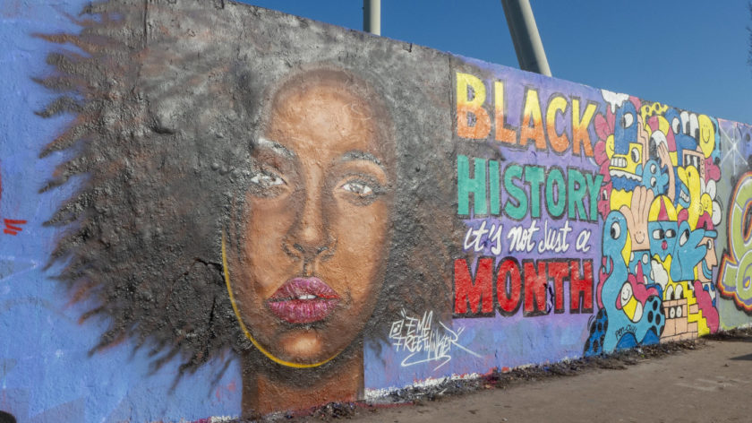 Zu sehen ist ein Graffiti-Portrait einer Schwarzen Frau an einer Mauer im Mauerpark in Berlin. Daneben steht der Schriftzug "Black History its not just a Month".