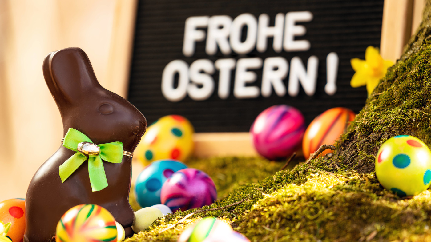 Osterhase aus Schokolade mit bunten Oster Eier mit der Nachricht Frohe Ostern.