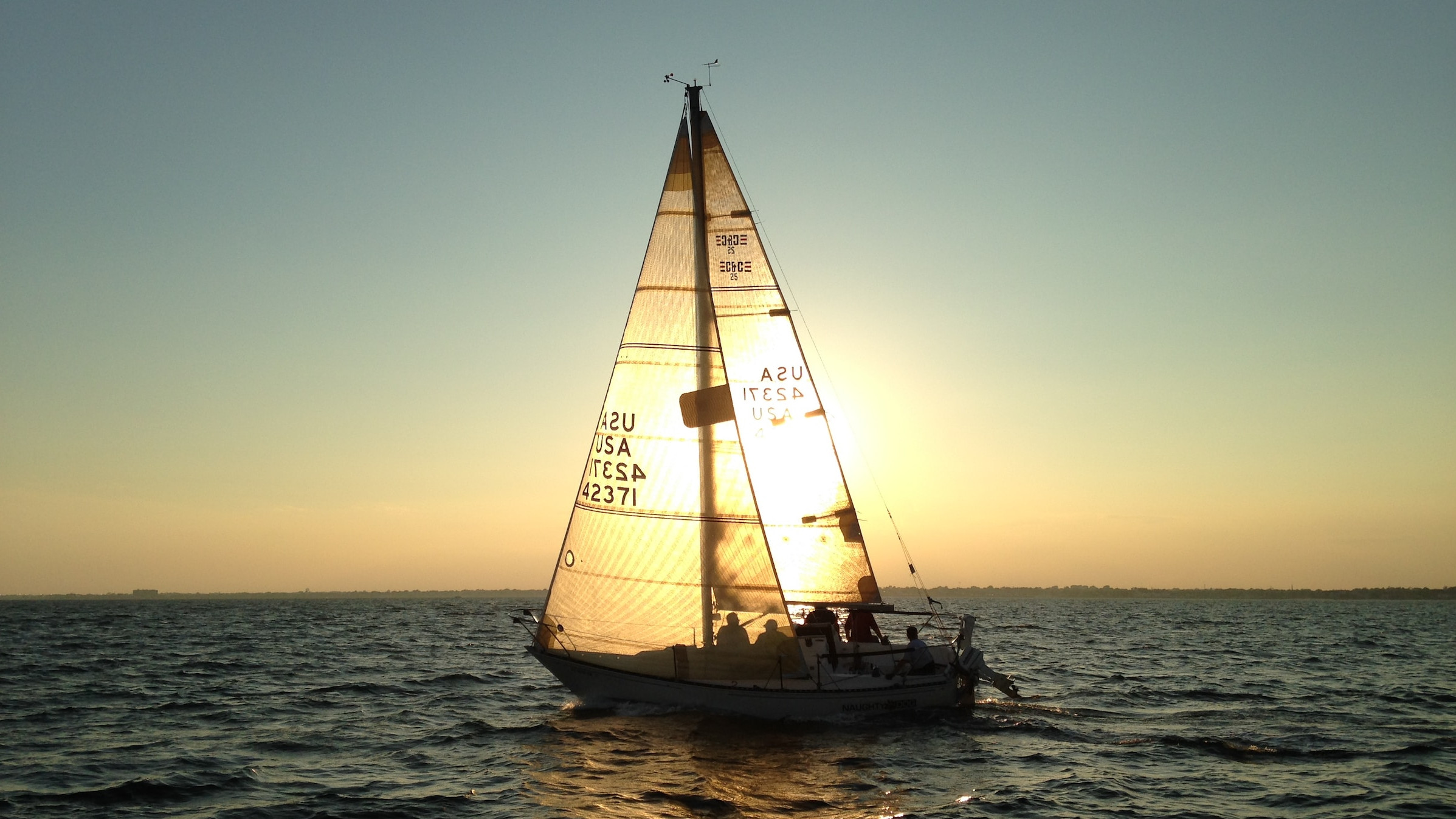 Menschen sitzen zusammen auf einem Segelboot im Sonnenuntergang.