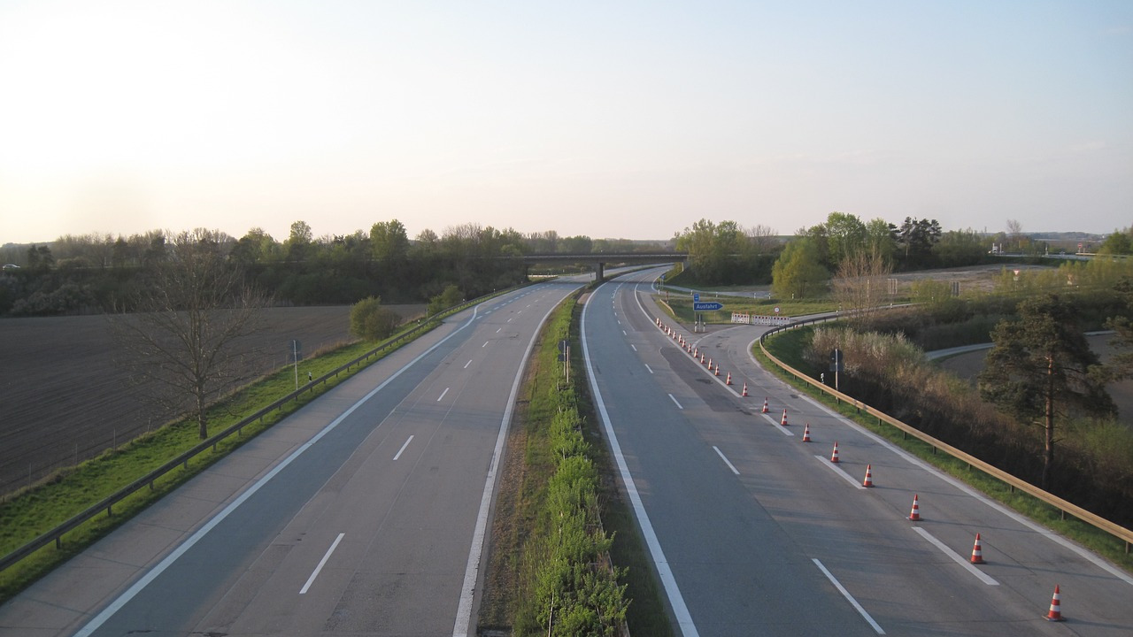 Das Foto zeigt eine Autobahn mit vier Spuren von einer Brücke aus gesehen. Kein einziges Auto ist unterwegs.