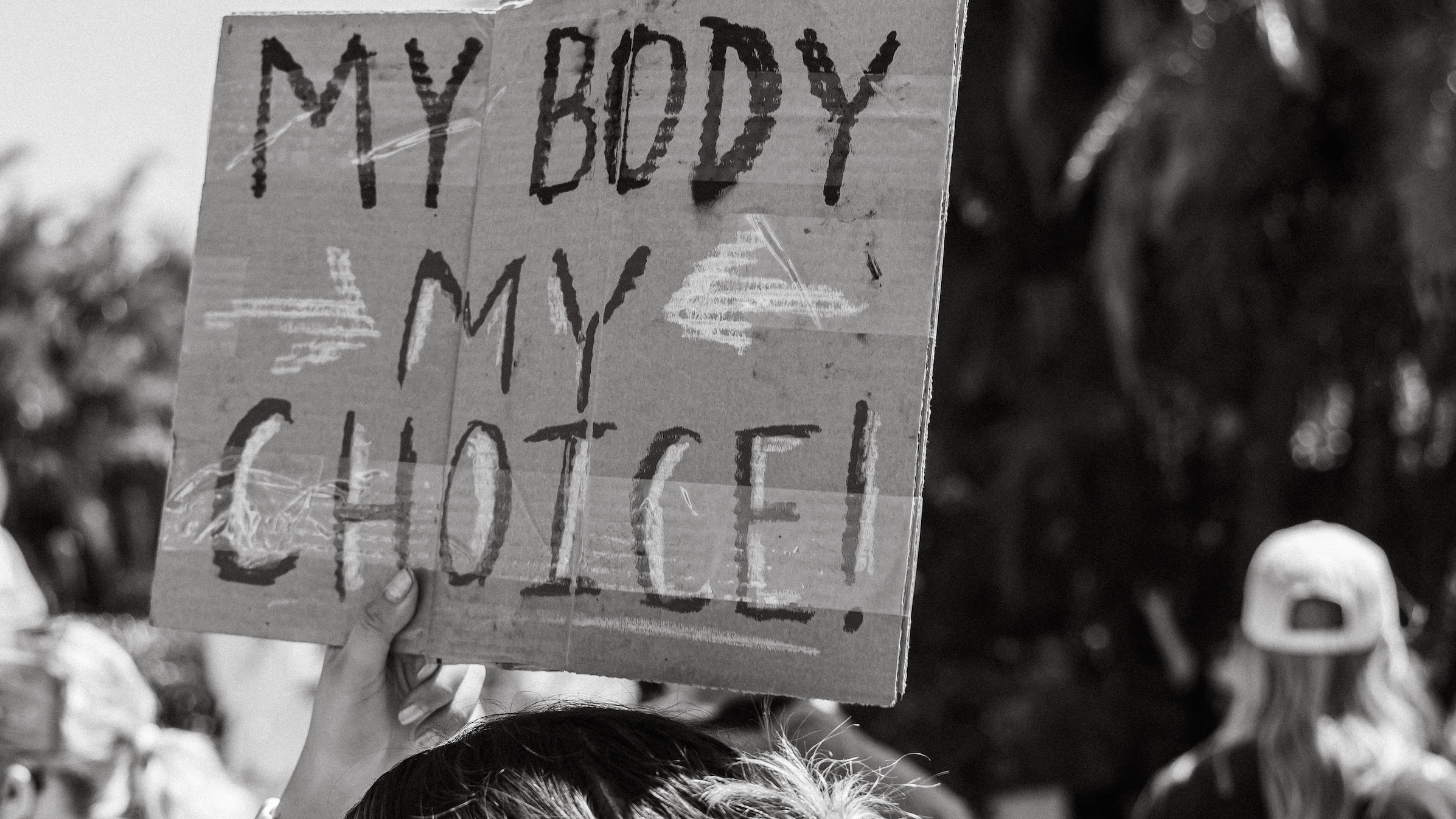 Eine Aufnahme von einer Demo: Eine Person hält ein Schild in die Luft, auf dem "My Body My Choice" steht.