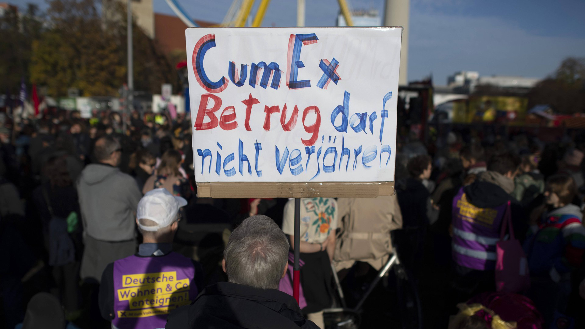 Ein Aktivist hält ein Plakat hoch. Darauf steht: CumEx-Betrug darf nicht verjähren