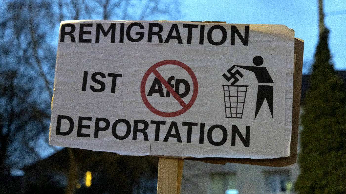 Ein Protest-Schild auf einer Demonstration gegen die AfD in Witten. 20. Januar 2024. Auf dem Schild steht: "Remigration ist Deportation". Daneben ist ein die abkürzung "AfD" in Rot durchgestrichen. Ein Piktogram zeigt eine Person, die ein Hakenkreuz in einen Mülleimer wirft.