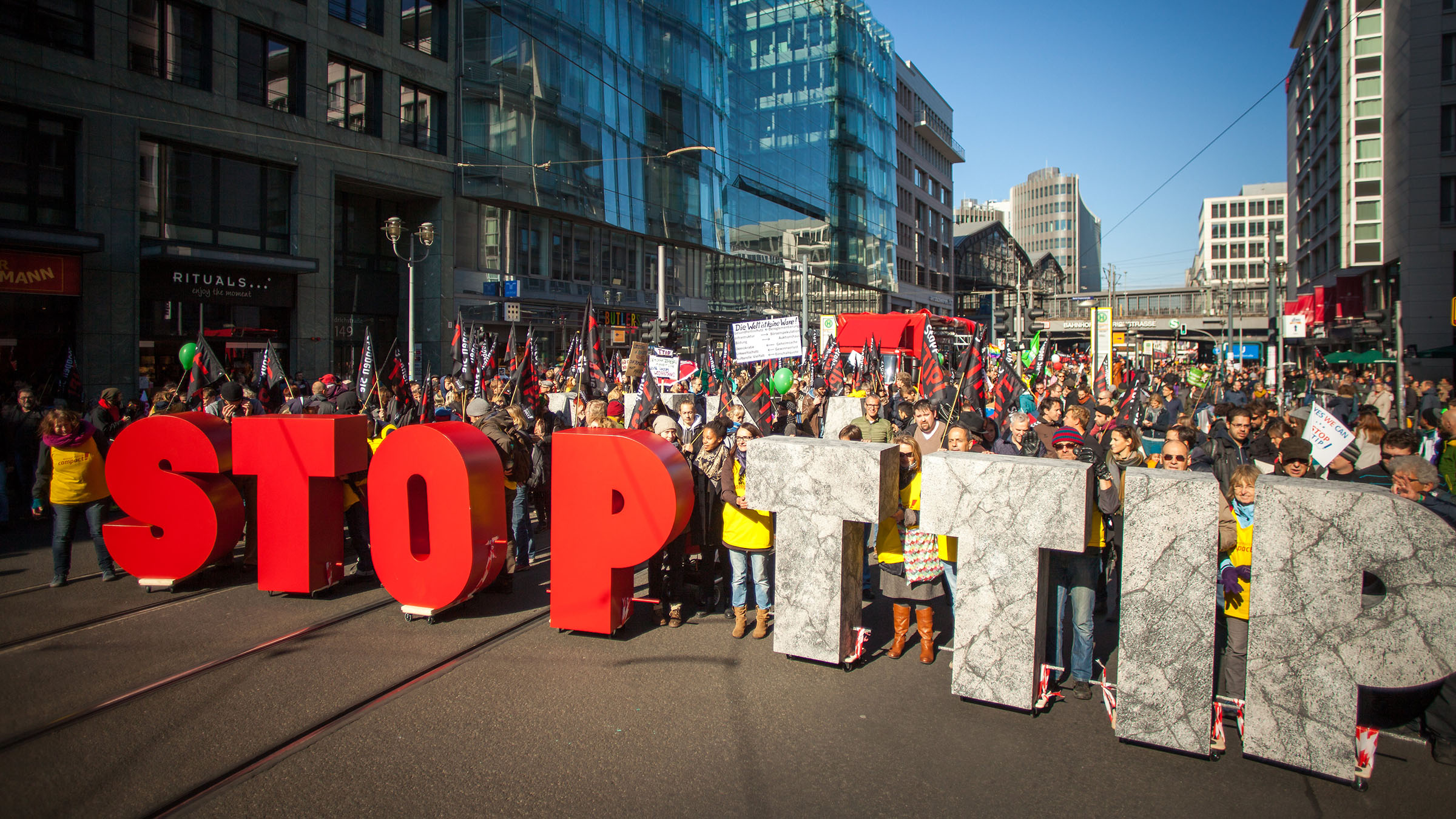 Hunderttausende demonstrieren gegen TTIP: In der Hand halten sie meterhohe Buchstaben, die Wörter "Stop TTIP" ergeben.