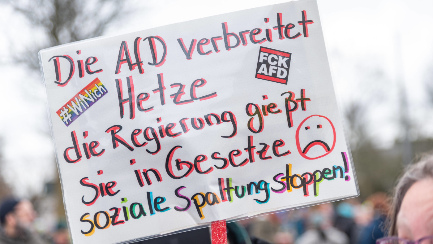 Ein Schild auf einer Demo, auf dem steht: "Die AfD verbreitet Hetze, die Regierung gießt sie in Gesetze. Soziale Spaltung stoppen!"