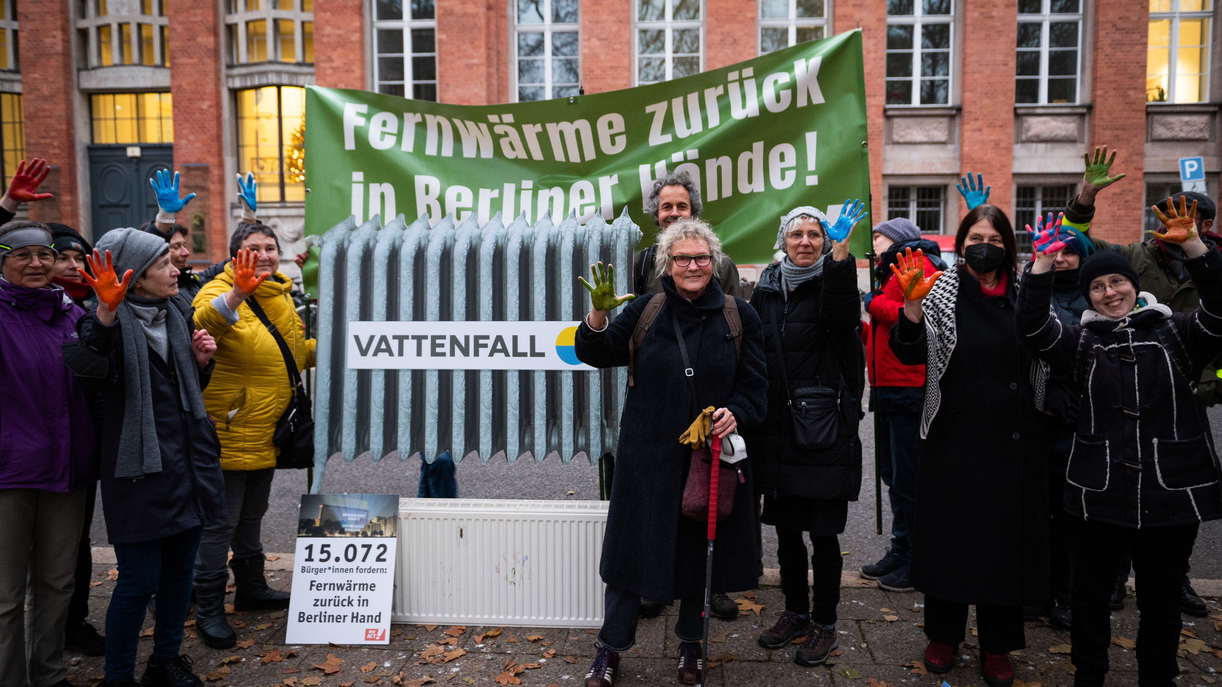 Petitionsübergabe an die damalige Umweltsenatorin Bettina Jarasch (Grüne). Auf einem großen Banner ist zu lesen: Fernwärme zurück in Berliner Hände! Aktive halten dazu ihre bunt bemalten Hände in die Höhe.
