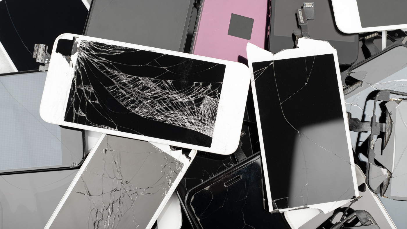 Viele kaputte Smartphones liegen übereinander. Manche haben kaputte Bildschirme, andere haben kaputte Hüllen.