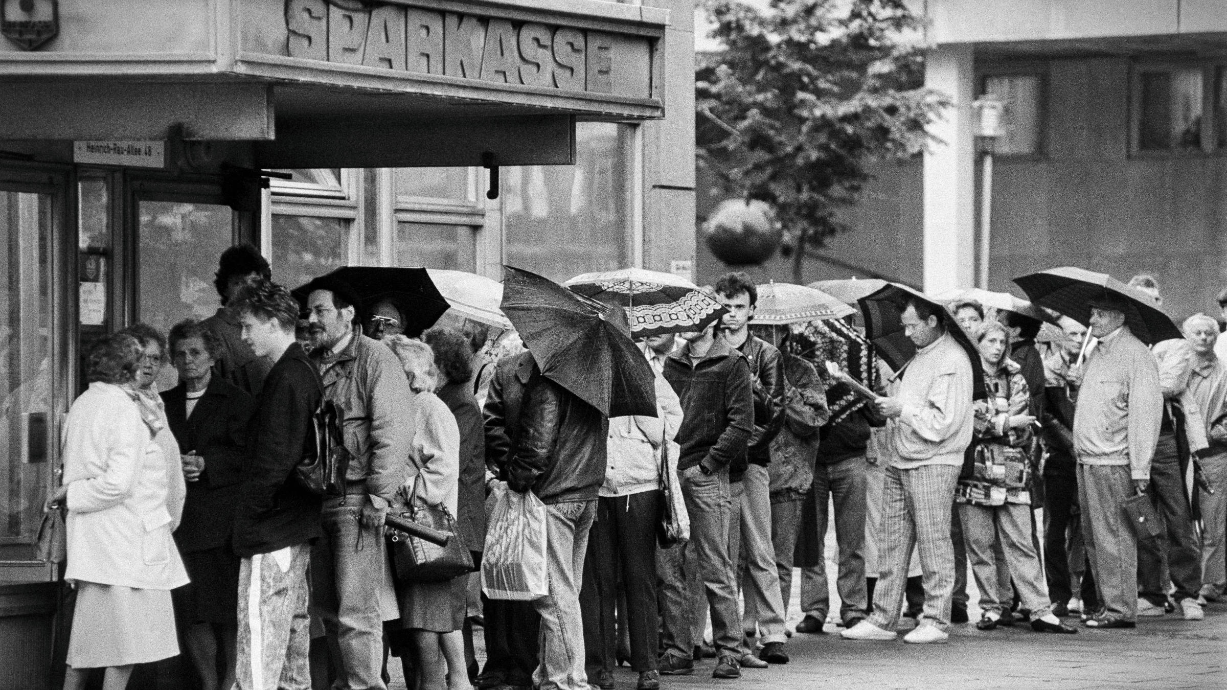 Vor einer DDR-Sparkasse in Potsdam in der Heinrich-Rau-Allee stehen Menschen an. Am 1. Juli 1990 trat die Währungsunion zwischen der DDR und der Bundesrepublik in Kraft. Nun konnte das Ostgeld gegen Westgeld ausgetauscht werden.