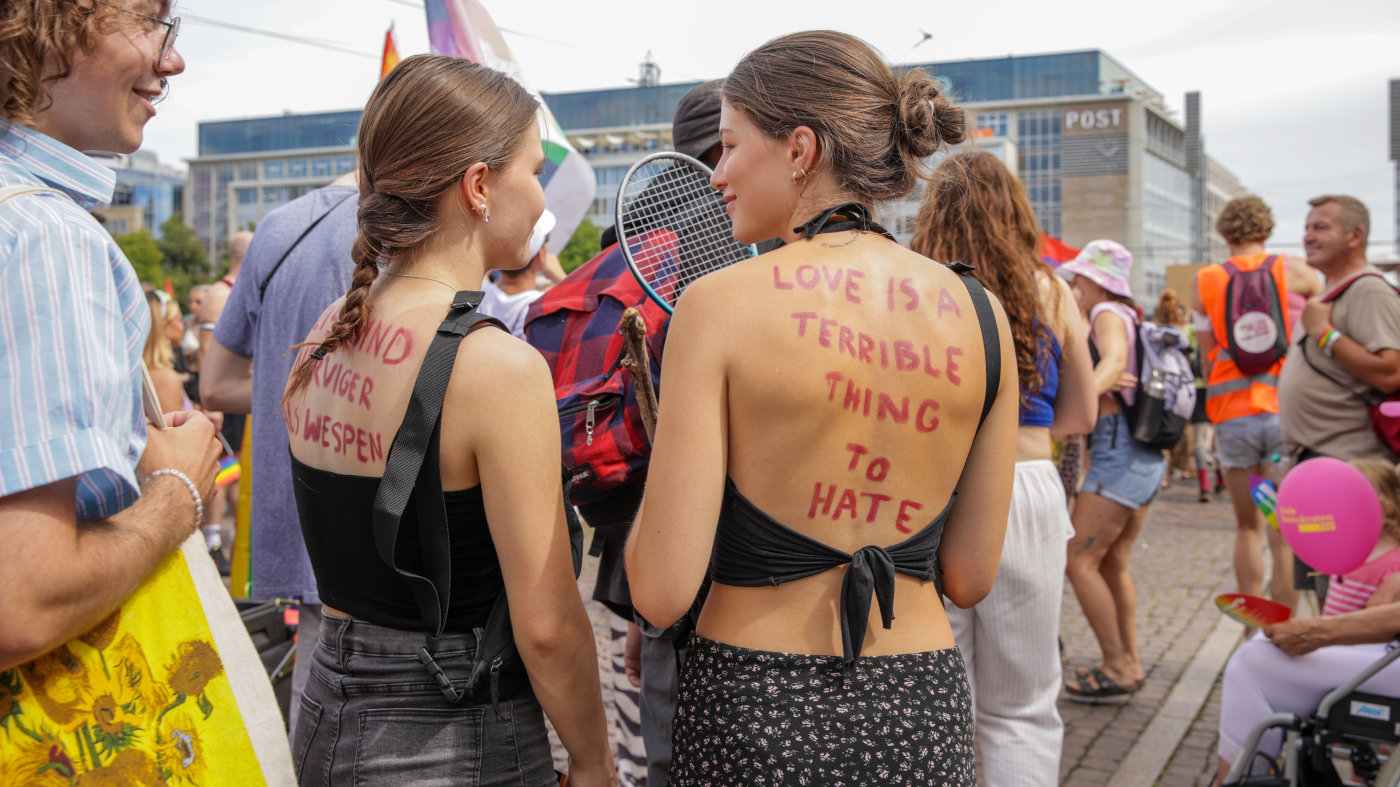 Foto vom CSD in Leipzig: Zwei Frauen stehen mit dem Rücken zu Kamera. Beide haben auf ihrem Rücken mit Lippenstift Botschaften geschrieben: "Nazis sind nerviger als Wespen" und "Love is a terrible thing to hate".