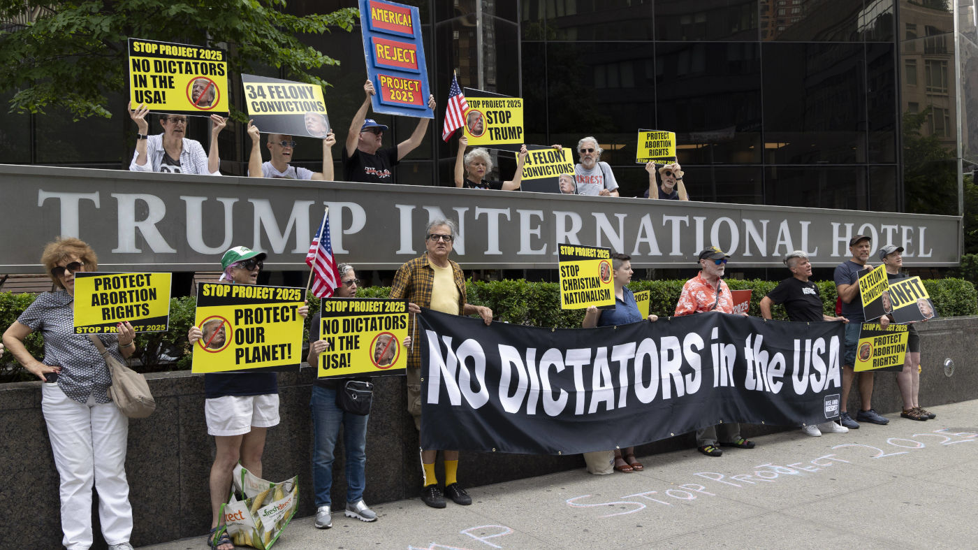 Mitglieder der Aktivisten-Gruppe "Rise & Resist" protestieren am 20. Juli gegen Trump und das "Project 2025" vor dem Trump-Tower in New York. Sie halten Schilder mit schwarzer Schrift auf gelben Untergrund, auf denen zum Beispiel steht (übersetzt): "Schützt unseren Planeten", "Keine Diktatoren in den USA" und "Stop Trump".