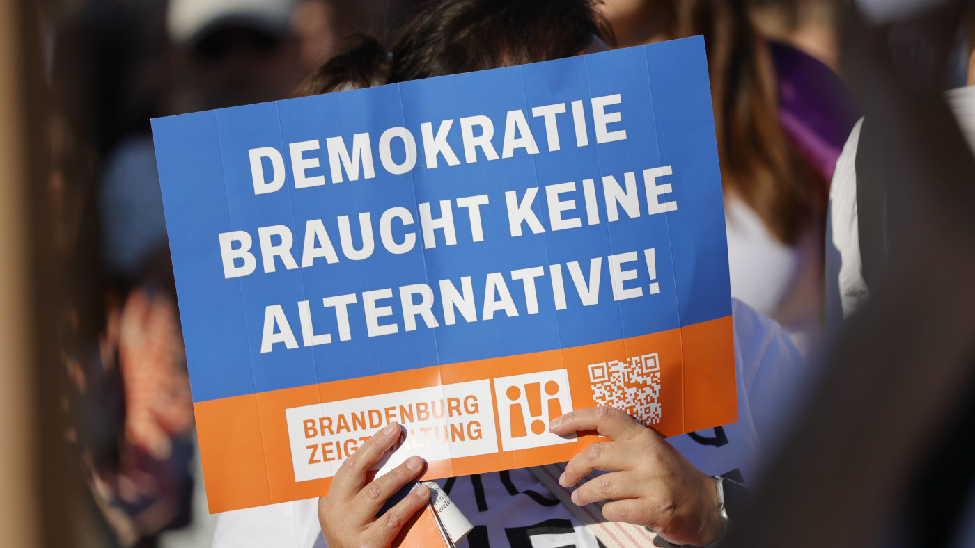 Demonstration am Rande der AfD-Wahlparty in Potsdam. Ein Protest-Teilnehmer hält ein Plakat hoch mit der Aufschrift: "Demokratie braucht keine Alternative! Brandenburg zeigt Haltung"