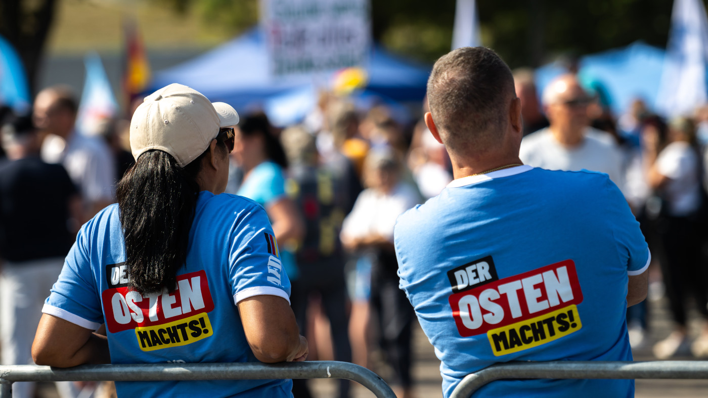 Zwei Teilnehmende einer AfD-Veranstaltung in Thüringen vor der Landtagswahl am 1. September. Sie tragen blaue T-Shirts mit dem Aufdruck "Der Osten machts".