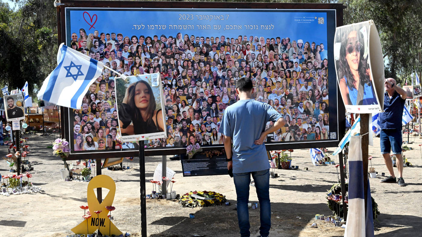 Ein Mann schaut sich eine große Collage aus Fotos an. Die Fotos zeigen die Opfer des Angriffes der Hamas auf das Nova Musikfestival am 7. Oktober 2023.