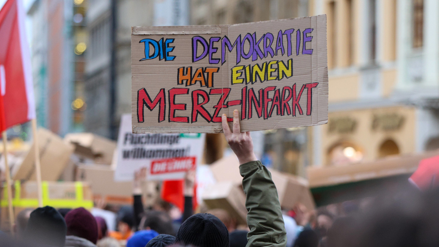 Ein Demo-Teilnehmer am 30. Januar 2025 in Leipzig hält ein Schild aus Pappe hoch. Darauf steht: "Die Demokratie hat einen Merz-Infakrt". Die Demo ist eine Reaktion auf die umstrittene Entscheidung von CDU-Chef Friedrich Merz, Beschlüsse mit der AfD in Kauf zu nehmen. Lies hier die Analyse von Felix Kolb dazu.