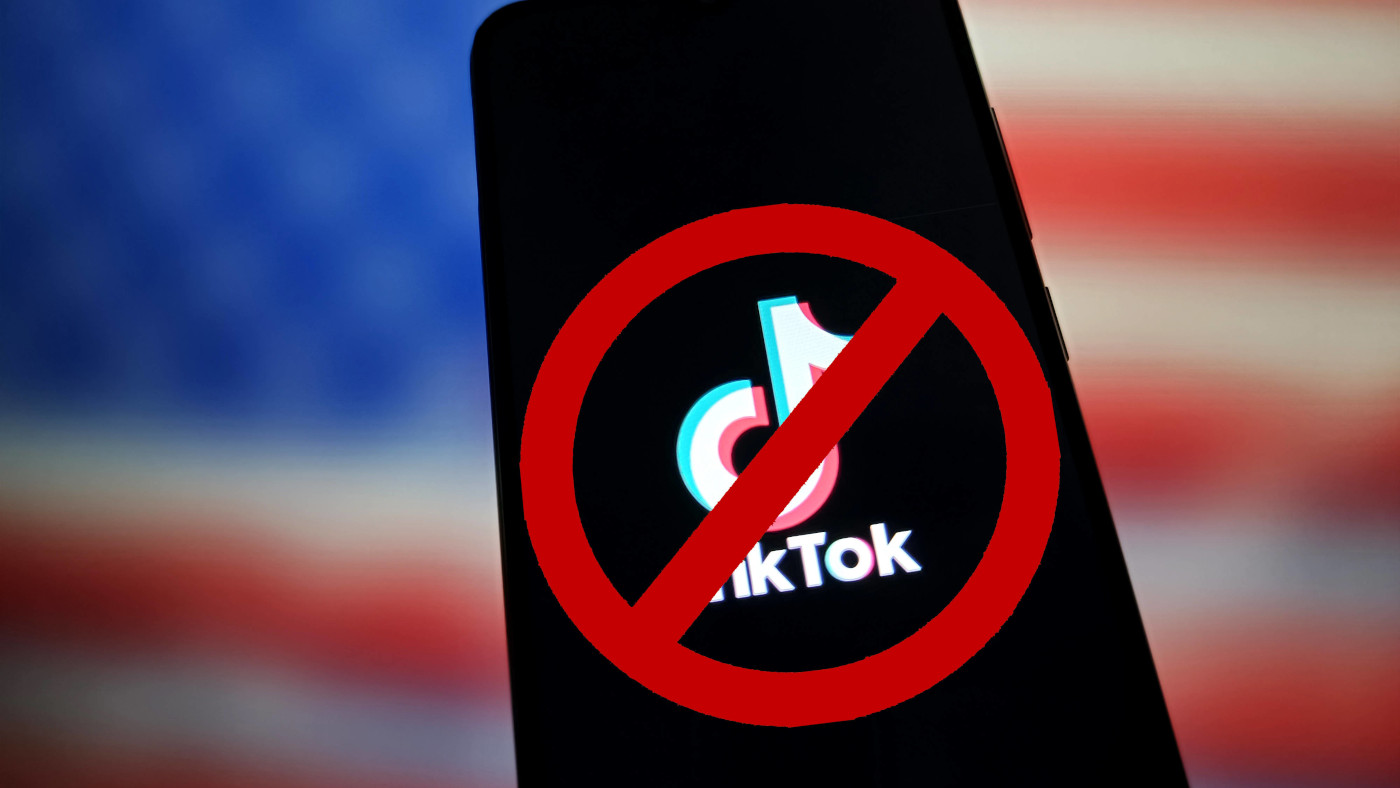 Eine Fotomontage zeigt ein Smartphone, welches das Logo von tikTok auf dem Bildschirm anzeigt, vor der US-amerikanischen Flagge. Das TikTok-Logo ist rot durchgestrichen.