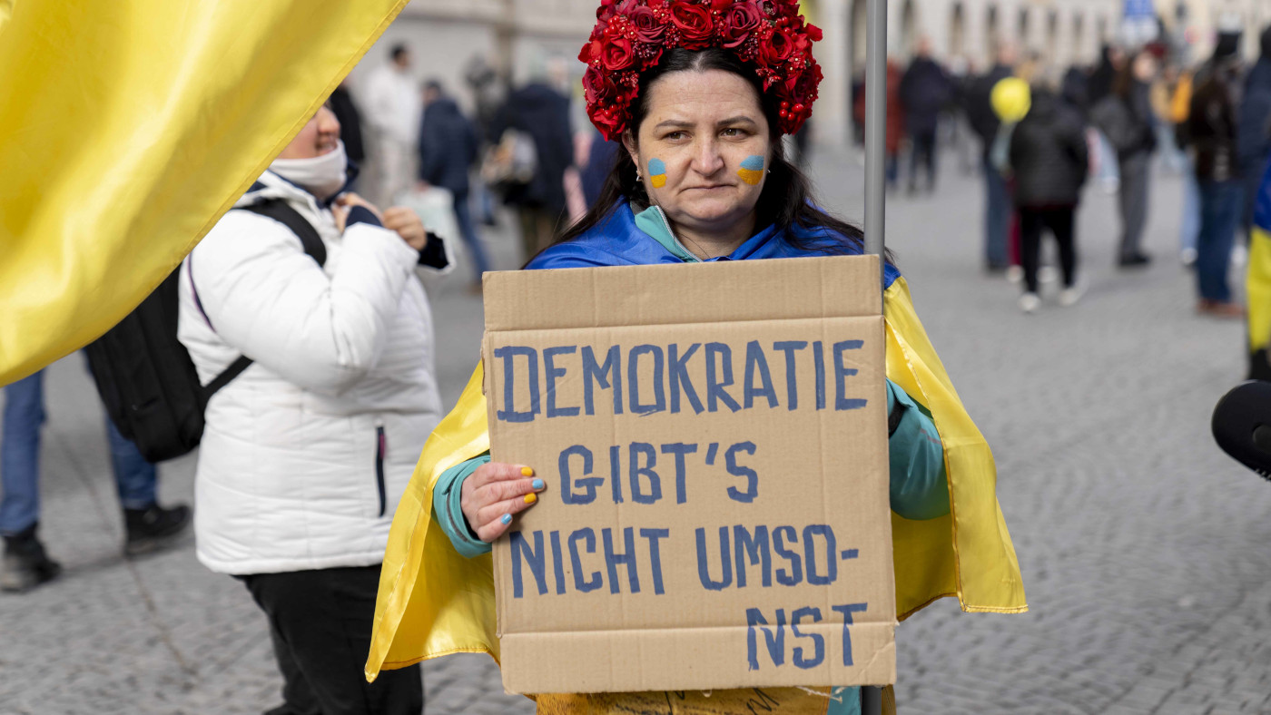 "Demokratie gibts nicht umsonst" steht auf dem Papp-Schild einer Protestantin vor der 61. Münchener Sicherheitskonferenz.