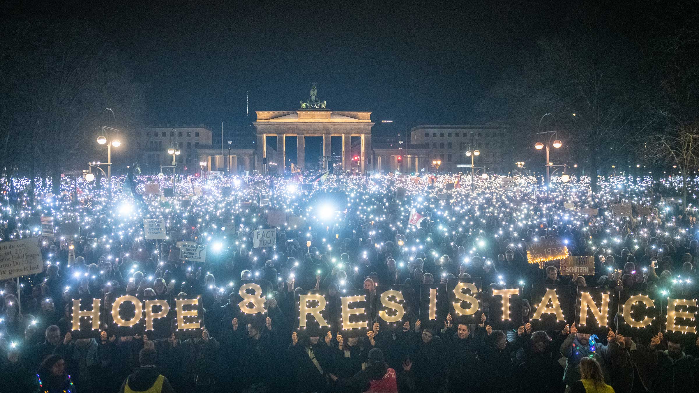 Tausende Teilnehmer beim Lichtermeer in Berlin. Im Vordergrund halten Teilnehmende leuchtende Buchstaben in die Höhe: Hope & Resistance (auf deutsch: Hoffnung und Widerstand)