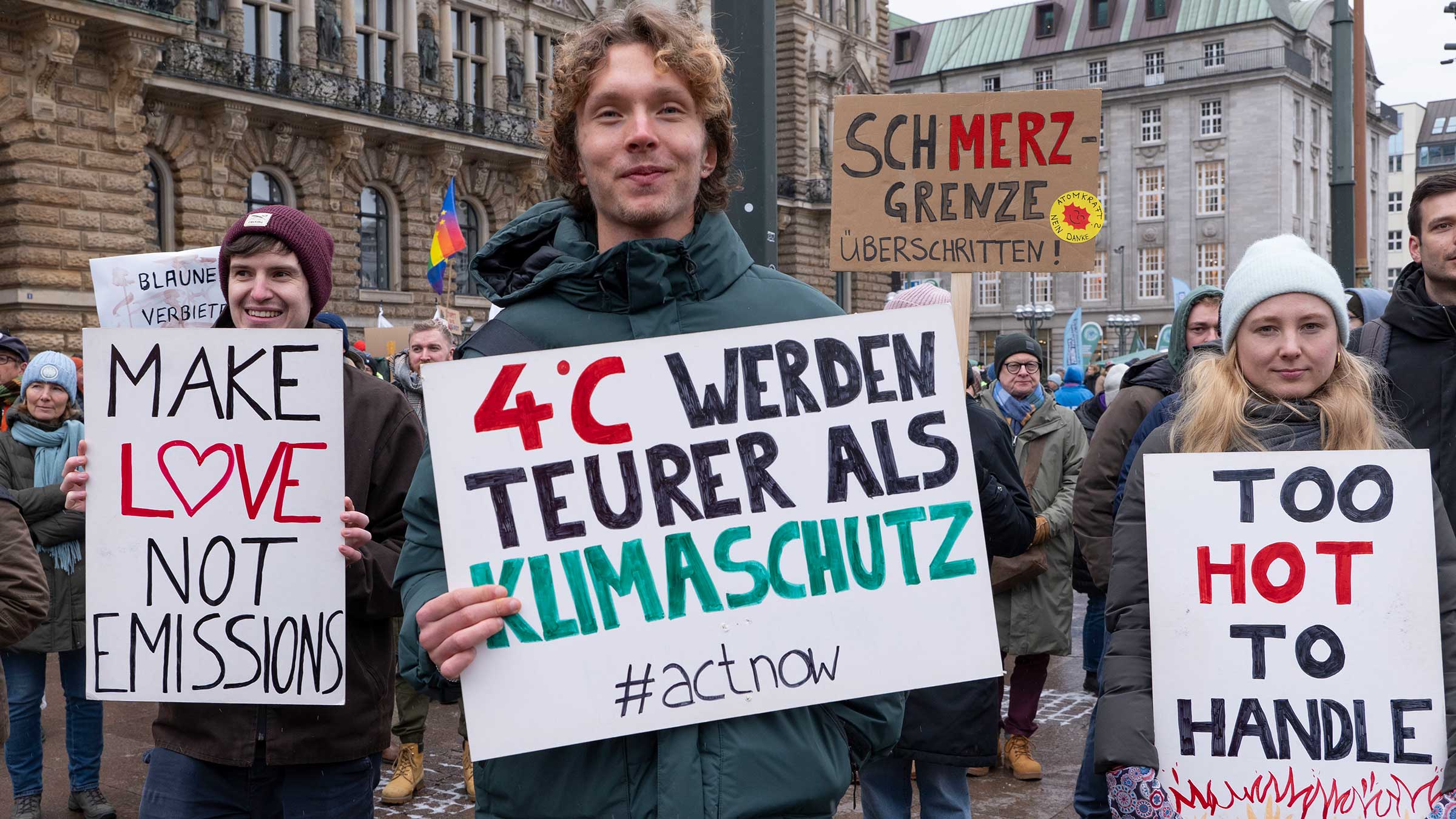 Drei Jugendliche beim Klimastreik in Hamburg. Sie halten alle Protestschilder in der Hand. Darauf steht: "4 Grad werden teurer als Klimschutz" und "Make love not emissions"